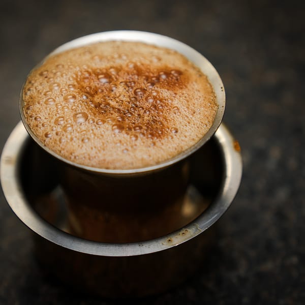 Close-up of a frothy South Indian filter coffee in a traditional metal dabara set.