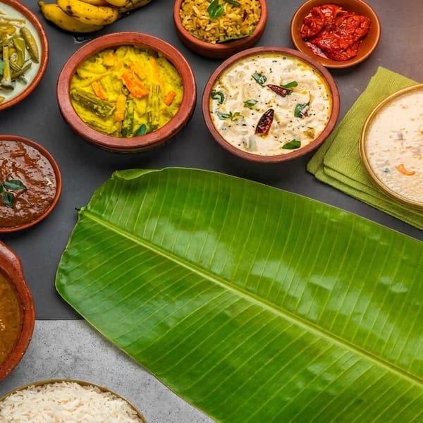 An overhead view of various Indian dishes in clay pots and bowls, with a banana leaf.
