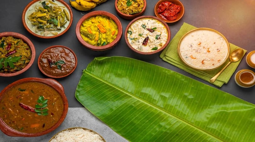 An overhead view of various Indian dishes in clay pots and bowls, with a banana leaf.